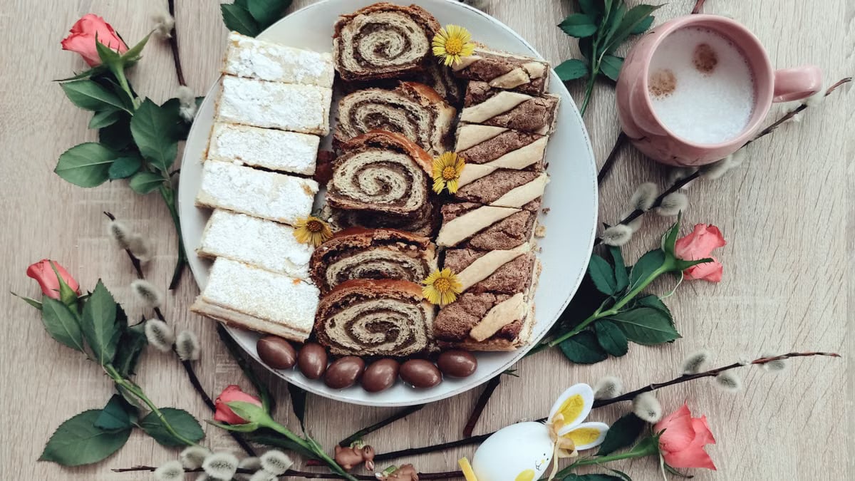 Top view of Easter desserts on a plate with coffee and spring flowers for a festive setting.